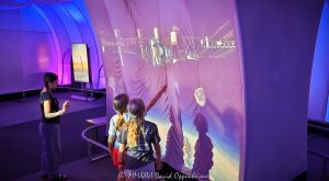 Adler Planetarium Interactive Spacewalk Exhibit in Chicago Adler Planetarium interactive spacewalk display in the Clark Family Welcome Gallery shows three young visitors gesturing toward a projected astronaut and the International Space Station. The immersive installation combines motion-sensing interaction, layered video projections, fabric surfaces, and blue-purple lighting inside the Museum Campus space museum in Chicago, Illinois – © 2026 David Oppenheimer – Performance Impressions photography archives https://performanceimpressions.com Adler Planetarium, Adler Planetarium Chicago, Adler Planetarium exhibit, Adler Planetarium interior, Clark Family Welcome Gallery, Welcome Gallery, Exploring Space, interactive spacewalk, spacewalk exhibit, astronaut exhibit, astronaut projection, interactive exhibit, interactive display, interactive projection, immersive exhibit, immersive display, immersive installation, motion sensing, motion sensor, gesture control, gesture controlled, visitor interaction, projection wall, video projection, projected image, space projection, spacewalk, astronaut, space station, International Space Station, ISS, space exploration, human spaceflight, outer space, space, stars, astronomy, astrophysics, planetarium, space museum, astronomy museum, science museum, museum, museum interior, museum exhibit, science exhibit, astronomy exhibit, space exhibit, educational exhibit, interactive museum, science education, space education, astronomy education, STEM, STEAM, children, girls, young visitors, museum visitors, visitors, interaction, hands, gestures, shadows, experiential learning, hands on learning, hands on exhibit, digital exhibit, digital media, interactive media, multimedia, multimedia exhibit, projection mapping, immersive media, exhibition design, exhibit design, interactive design, museum design, visual technology, display technology, motion detection, space simulation, astronaut spacewalk, astronaut floating, astronaut in space, space station platform, orbital station, orbit, microgravity, space science, space technology, cosmic imagery, star field, blue lighting, purple lighting, LED lighting, colored lighting, dramatic lighting, illuminated exhibit, fabric walls, fabric panels, sheer fabric, projection fabric, aluminum tubing, futuristic interior, futuristic design, futuristic architecture, Thomas Roszak Architecture, Thomas Roszak Architects, Snibbe Interactive, Second Story, Graham Plumb, Clark Family, Grainger Sky Theater, Museum Campus, Chicago Museum Campus, Northerly Island, Chicago lakefront, 1300 South DuSable Lake Shore Drive, 1300 S DuSable Lake Shore Dr, 1300 South Lake Shore Drive, 1300 S Lake Shore Drive, Chicago, Chicago Illinois, Chicago IL, Illinois, 60605, Chicago attraction, Chicago museum, Chicago science museum, Chicago planetarium, family attraction, educational attraction, cultural institution, nonprofit, 501c3, Museums in the Park, Chicago Park District, United States, licensing, image licensing, commercial imagery, photography licensing, art, print, fine art, commercial photography, David Oppenheimer, horizontal, 1-15213827141