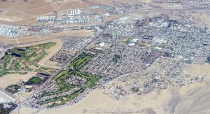 Boulder City, Nevada seen from above, showing Boulder Creek Golf Club, Boulder City Golf Course, Boulder City High School, and surrounding desert neighborhoods – © 2025 David Oppenheimer – Performance Impressions aerial photography archives – https://performanceimpressions.com Boulder City, Boulder City Nevada, Boulder City aerial, Boulder City real estate, Boulder Creek Golf Club, Boulder City Golf Course, Southern Nevada Veterans Memorial Cemetery, Boulder City High School, Nature Discovery Trail and Rock Garden, Bootleg Canyon Park Trail Head, golf, golf course, golf club, golfing, fairway, greens, public golf, municipal golf, desert golf, aerial, aerial view, aerial photo, aerial photography, top down, map view, layout, desert, sand, beige, dry terrain, desert city, city layout, cityscape, homes, neighborhoods, real estate, home lots, community planning, urban layout, grid layout, roadways, regional planning, residential development, Southern Nevada, Southwest, Clark County, Las Vegas area, Nevada town, outdoor space, recreation, green space, open space, elevation, scenic, travel, tourism, United States, western US, architecture, sky view, outdoor lifestyle, infrastructure, landscaping, nature trail, school campus, trailhead, park access, horizontal, 1-14993092111