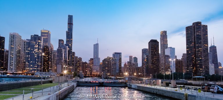 Chicago Harbor Lock in Chicago, Illinois, connects Lake Michigan with the Chicago River beneath the downtown skyline after sunset. City lights line the waterfront under a blue-hour sky, with navigation lights marking the lock and the breakwater visible at the Chicago Harbor entrance – © 2026 David Oppenheimer – Performance Impressions photography archives https://performanceimpressions.com Chicago Harbor Lock, Chicago Harbor, Chicago Lock, Chicago River Lock, Chicago Harbor entrance, Lake Michigan, Chicago River, river mouth, Chicago skyline, Chicago cityscape, downtown Chicago, Chicago lakefront, Chicago waterfront, Chicago, Chicago Illinois, Chicago IL, Illinois, 60611, sunset, Chicago sunset, blue hour, twilight, dusk, evening, lights, city lights, skyline lights, building lights, navigation lights, illuminated skyline, sunset sky, clouds, cloudscape, dramatic sky, skyline, cityscape, landscape, downtown, city, urban, buildings, skyscrapers, towers, architecture, lake, water, river, harbor, harbor lock, navigation lock, lock, navigation, maritime, waterway, channel, breakwater, jetty, lock gates, infrastructure, lakefront, waterfront, shoreline, horizon, United States, licensing, image licensing, commercial imagery, photography licensing, art, print, fine art, commercial photography, David Oppenheimer, horizontal, 1-15213827141