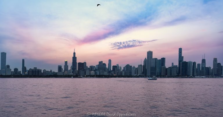 Chicago skyline panorama from Lake Michigan at blue hour, spanning roughly two miles of the city’s lakefront from the South Loop through downtown to the Near North Side. Vertical towers extend across the horizon beneath violet, orange, and blue post-sunset clouds as the lake reflects the remaining evening light in Chicago, Illinois – © 2026 David Oppenheimer – Performance Impressions photography archives https://performanceimpressions.com Chicago cityscape, cityscape, Chicago skyline, skyline, Chicago skyline panorama, Chicago panorama, panoramic cityscape, panoramic skyline, panorama, panoramic, Chicago blue hour, Lake Michigan, Chicago lakefront, Chicago waterfront, Chicago coastline, Chicago coast, Chicago lakeshore, lakefront, waterfront, coastline, coast, lakeshore, shoreline, water, lake, horizon, downtown Chicago, South Loop, Chicago Loop, Loop Chicago, Lakeshore East, New Eastside, Streeterville, Near North Side, Grant Park, Millennium Park, Chicago, Chicago Illinois, Chicago IL, Illinois, urban landscape, landscape, downtown, city, urban, blue hour, twilight, dusk, after sunset, evening, evening light, glowing sky, purple sky, violet sky, orange sky, blue sky, clouds, cloudscape, city lights, skyline lights, building lights, reflections, lake reflection, gull, seagull, bird, bird in flight, architecture, buildings, skyscrapers, towers, high rise, office towers, residential towers, apartments, condominiums, hotels, mixed use, real estate, Chicago real estate, lakefront real estate, waterfront real estate, commercial real estate, residential real estate, 1000M, 1000M Apartments, 1000 S Michigan Ave, Sentral Michigan Avenue, Essex on the Park, 808 S Michigan Ave, Hilton Chicago, Stevens Hotel, 720 S Michigan Ave, Willis Tower, Sears Tower, 233 S Wacker Drive, 311 South Wacker, 311 S Wacker Drive, Aon Center, Standard Oil Building, Amoco Building, 200 E Randolph Street, The St. Regis Chicago, St. Regis Chicago, Vista Tower, Wanda Vista Tower, 875 North Michigan Avenue, John Hancock Center, 360 Chicago, Aqua, Aqua Chicago, One Prudential Plaza, Two Prudential Plaza, Blue Cross Blue Shield Tower, 340 on the Park, Helmut Jahn, Skidmore Owings Merrill, SOM, Bruce Graham, Fazlur Rahman Khan, Kohn Pedersen Fox, KPF, Edward Durell Stone, Studio Gang, Jeanne Gang, Chicago skyline art, Chicago cityscape art, Chicago art, Chicago photography, panoramic photography, blue hour photography, skyline photography, cityscape photography, landscape photography, architectural photography, panorama art, skyline art, cityscape art, landscape art, urban art, artwork, photo art, wall art, art print, Chicago print, skyline print, travel, tourism, destination, United States, licensing, image licensing, commercial imagery, photography licensing, art, print, fine art, commercial photography, David Oppenheimer, horizontal, 1-15213827141