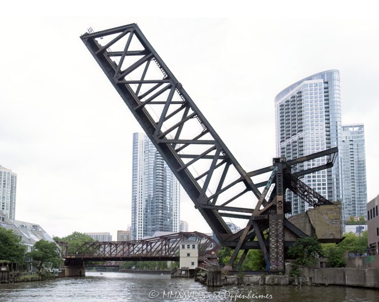 Chicago and North Western Railway Kinzie Street Bridge raised over the North Branch of the Chicago River in downtown Chicago, Illinois. Historic single-leaf bascule railroad bridge near Kinzie Street and Canal Street, also known as the Carroll Avenue Bridge, built in 1908 and designated a Chicago Landmark in 2007. The raised steel bridge is a former Chicago and North Western railroad span now owned by Union Pacific – © 2026 David Oppenheimer – Performance Impressions photography archives https://performanceimpressions.com Chicago and North Western Railway Bridge, Chicago & North Western Railway Bridge, Chicago and North Western Railroad Bridge, Chicago & North Western Railroad Bridge, Kinzie Street railroad bridge, Kinzie Street Railroad Bridge, Kinzie Street Bridge, Carroll Avenue Bridge, C&NW bridge, C&NW railroad bridge, Union Pacific bridge, Union Pacific Railroad, raised bridge, bridge, raised railroad bridge, open bridge, bascule bridge, single-leaf bascule bridge, railroad bridge, railway bridge, rail bridge, train bridge, steel bridge, steel girders, bridge girders, metal girders, steel truss, truss bridge, railroad truss, steel structure, bridge structure, riveted steel, steelwork, historic bridge, landmark bridge, Chicago Landmark, Chicago bridge, Chicago bridges, Chicago railroad bridge, Chicago railway bridge, Chicago River bridge, Chicago River, North Branch Chicago River, North Branch, Kinzie Street, Canal Street, Wolf Point, downtown Chicago, Chicago Loop, River North, Near West Side, Chicago, Chicago Illinois, Illinois, United States, 60654, architecture, Chicago architecture, architectural photography, bridge architecture, engineering, civil engineering, structural engineering, industrial architecture, transportation, transportation infrastructure, rail infrastructure, railroad infrastructure, railway infrastructure, railroad history, railway history, Chicago history, industrial history, historic infrastructure, urban infrastructure, bridge photography, railroad photography, rail photography, infrastructure photography, documentary photography, editorial photography, commercial photography, commercial imagery, image licensing, licensing, photography licensing, David Oppenheimer, horizontal, 1-15156784411