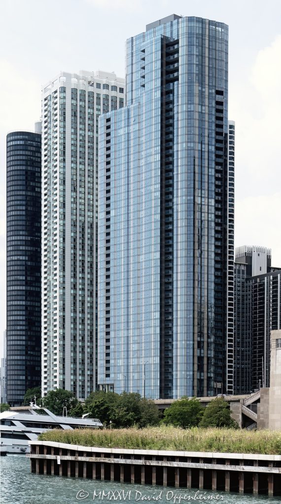 Cirrus Condominiums at 211 North Harbor Drive in Chicago, Illinois, located in Lakeshore East near Lake Michigan, the Chicago River, and DuSable Harbor. Contemporary residential high-rise architecture by bKL Architecture featuring a continuous glass facade, bronze-toned metal panels, balconies, and luxury condominium residences. The view primarily features Cirrus, with nearby 195 North Harbor Drive and 155 Harbor Condominium also visible along the Harbor Drive lakefront – © 2026 David Oppenheimer – Performance Impressions photography archives https://performanceimpressions.com Cirrus Condominiums, Cirrus Chicago, Cirrus, Cirrus condos, Cirrus condominium tower, 211 North Harbor, 211 North Harbor Drive, 211 N Harbor, North Harbor Drive, Harbor Drive, Lakeshore East, Chicago, Chicago Illinois, Illinois, United States, 60601, Downtown Chicago, Chicago Loop, New Eastside, Chicago River, Chicago lakefront, Lake Michigan, architecture, Chicago architecture, architectural photography, facade, building exterior, exterior, residential architecture, modern architecture, contemporary architecture, urban architecture, condominium tower, condominium building, condo tower, condo building, residential tower, residential building, high-rise, skyscraper, building, tower, glass tower, glass building, glass facade, continuous glass facade, bronze panels, metal panels, balconies, balcony, luxury condos, Chicago condos, Lakeshore East condos, downtown condos, residential real estate, condominium real estate, Chicago real estate, real estate, urban living, city living, lakefront living, riverfront architecture, waterfront, downtown, urban, iconic building, American architecture, Illinois architecture, daylight, bKL Architecture, Lendlease, Magellan Development Group, Cascade Park, Cascade Apartments, 195 North Harbor, 195 North Harbor Drive, 155 Harbor, 155 North Harbor, Harbor Point, 155 Harbor Condominium, commercial photography, commercial imagery, image licensing, licensing, photography licensing, art, print, fine art, David Oppenheimer, vertical, 1-15156784411