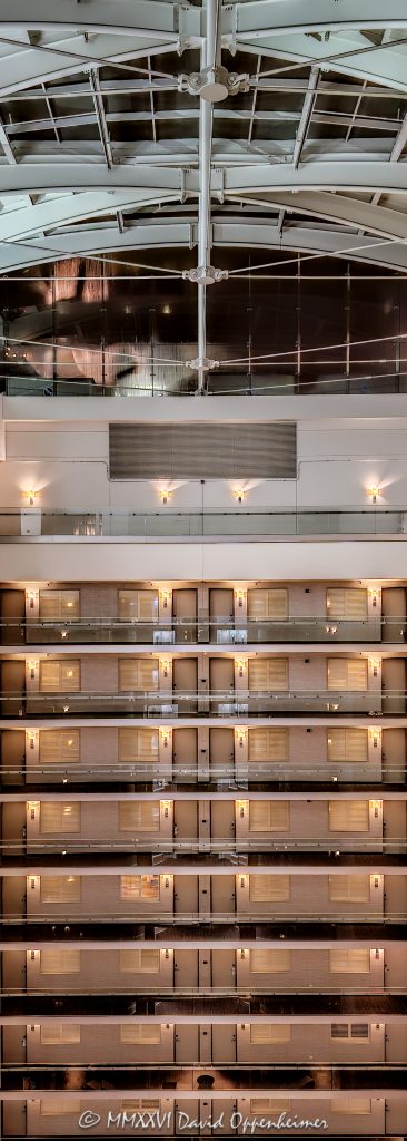 Embassy Suites by Hilton Chicago Downtown Magnificent Mile atrium interior in Chicago, Illinois, showing approximately eight upper levels of stacked guestroom corridors across the vast open interior, with strong horizontal and vertical lines rising to the curved steel framing and glazed roof structure above – © 2026 David Oppenheimer – Performance Impressions photography archives https://performanceimpressions.com Embassy Suites by Hilton Chicago Downtown Magnificent Mile, Embassy Suites Chicago Downtown Magnificent Mile, Embassy Suites Chicago Magnificent Mile, Embassy Suites Magnificent Mile, Embassy Suites Chicago, Embassy Suites by Hilton, Embassy Suites, Embassy Suites atrium, Embassy Suites interior, Chicago Embassy Suites, 511 North Columbus Drive, 511 N Columbus Drive, 511 N Columbus Dr, 60611, hotel atrium, atrium interior, Chicago hotel atrium, Chicago hotel interior, hotel interior, atrium architecture, interior architecture, hotel architecture, open atrium, multi-story atrium, tall atrium, soaring atrium, glass atrium, atrium roof, vaulted atrium, vaulted roof, glass roof, metal roof, roof structure, roof framing, roof glazing, skylight, skylight roof, steel framing, structural steel, steel beams, steel girders, arched beams, steel arches, curved steel, curved beams, roof girders, tension rods, structural rods, support cables, structural cables, horizontal lines, vertical lines, linear geometry, architectural geometry, geometric architecture, repeating lines, repetition, architectural pattern, guest corridors, guestroom corridors, hotel corridors, interior corridors, open corridors, atrium corridors, upper floors, hotel floors, guestroom doors, interior walkways, structural engineering, engineering, architectural engineering, structural design, building structure, steel structure, hospitality architecture, hospitality design, interior design, commercial interior, commercial architecture, high-rise hotel, hotel tower, all-suite hotel, all suite hotel, upscale hotel, full service hotel, Chicago hotel, downtown Chicago hotel, Streeterville hotel, Magnificent Mile hotel, Chicago hospitality, Streeterville, River East, River East Chicago, River East Center, Magnificent Mile, downtown Chicago, Near North Side, Chicago, Chicago Illinois, Illinois, United States, USA, Embassy Suites Chicago Downtown-Lakefront, Embassy Suites Downtown Lakefront, Chicago Downtown Lakefront, DeStefano + Partners, DeStefano and Partners, DeStefano Partners, Greg Randall, architect, architecture firm, The Gettys Group, Gettys Group, Gettys, interior designer, MCL Companies, MCL, developer, Hilton, Hilton Worldwide, Hilton Worldwide Holdings, HLT, NYSE HLT, Hilton stock, Host Hotels & Resorts, Host Hotels, Host Hotels and Resorts, HST, NASDAQ HST, hotel REIT, hospitality, hotel, atrium, interior, architecture, structure, steel, glass, glazing, Art Deco, Art Deco influence, contemporary design, architectural photography, interior photography, hotel photography, Chicago architecture photography, structural photography, fine art photography, architectural print, photographic print, archival print, gallery print, collector print, wall art, Chicago architecture art, licensing, image licensing, commercial imagery, photography licensing, art, print, fine art, commercial photography, David Oppenheimer, David Oppenheimer photography, Performance Impressions, Performance Impressions photography archives, vertical, 1-15213827141