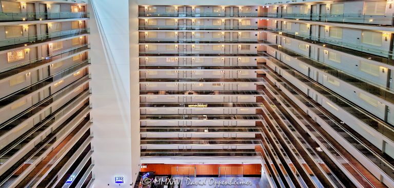 Embassy Suites by Hilton Chicago Downtown Magnificent Mile atrium interior in Streeterville, Chicago, Illinois, showing three sides of the vast open central volume with approximately a dozen visible levels of stacked guestroom corridors and walkways. Repeating railings, floor edges and strong horizontal and vertical lines create an almost abstract geometric composition emphasizing the hotel’s multi-story atrium architecture and contemporary Art Deco-influenced design – © 2026 David Oppenheimer – Performance Impressions photography archives https://performanceimpressions.com