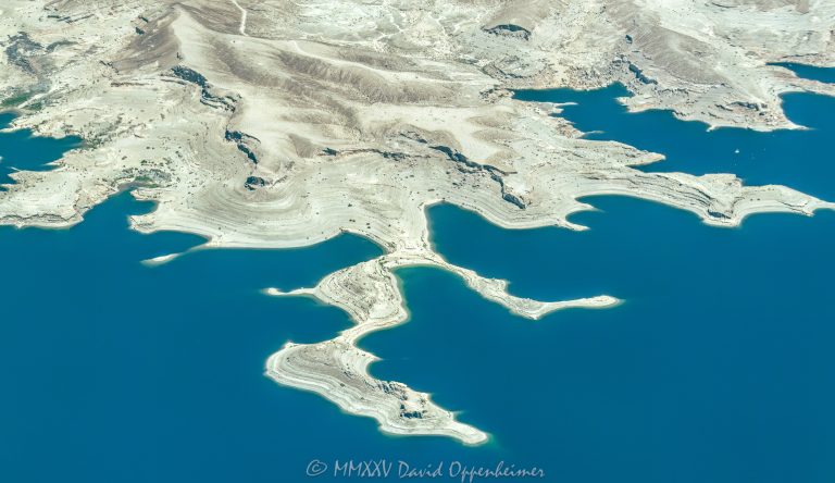 Lake Mead shoreline and Battleship Rock in the Lake Mead National Recreation Area between Swallow Bay and Water Barge Cove near Callville Bay, Nevada aerial view – © 2025 David Oppenheimer – Performance Impressions aerial photography archives - https://performanceimpressions.com Lake Mead, Lake Mead aerial, Swallow Bay, Water Barge Cove, Callville Bay, lakefront, shoreline, shore, waterline, water level, Circle of Rocks, Lovers Cove, Hidden Cove, Hideaway Cove, Quiet Cove, lake, lake aerial, desert lake, Colorado River, Clark County, Lake Mead National Recreation Area, Nevada, water, drinking water, water supply, river, plateau, siltstone, sandstone, boating, channel, geology, ravine, canyon, valley, aerial, aerial view, mountains, arid, barren, vacation, gorge, rim, red, cliffs, aerial photographer, Battleship Rock aerial, wash, erosion, rocks, erode, scenic, landscape, overlook, rocky, visit, travel, American West, desert, high desert, advertising, United States, USA, America, horizontal, 1-14993092111