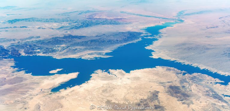 Lake Mead wide angle aerial view showing the greater Lake Mead National Recreation Area along the Nevada Arizona border including Anglerfish Island, Borellie Bay, Bonellie Landing, Overton Arm, Echo Bay, the Virgin River, Virgin Basin, Jimbilnan Wilderness, Middle Point Islands, the Black Mountains, the Muddy Mountains, Valley of Fire State Park, and Big Gypsum Ledges – © 2025 David Oppenheimer – Performance Impressions aerial photography archives – https://performanceimpressions.com Lake Mead, Lake Mead aerial, reservoir, border, Anglerfish Island, Borellie Bay, Bonellie Landing, Overton Arm, Echo Bay, Virgin River, Virgin Basin, Middle Point Islands, Black Mountains, wide angle, panoramic, Muddy Mountains, Valley of Fire State Park, Valley of Fire, Big Gypsum, Big Gypsum Ledges, Gypsum Reefs, Detrital Reefs, Stewart Cliffs, Middle Point, Napoleon's Tomb, Boat Wreck Point, Manganese Wash, Jimbilnan Wilderness, Guardian Peak, The Narrows, Boulder Wash Cove, Debbies Cove, Boathouse Cove, Crescent Cove, Ebony Cove, Kendal Cove, Catclaw Cove, Horseshoe Cove, Hallett Cove 2.0, Secret Cove, Alkali Spring Cove, lakefront, shoreline, shore, waterline, water level, lake, lake aerial, desert lake, Colorado River, Clark County, Lake Mead National Recreation Area, Arizona, Nevada, water, drinking water, water supply, river, plateau, siltstone, sandstone, boating, channel, geology, ravine, canyon, valley, aerial, aerial view, mountains, arid, barren, vacation, gorge, rim, red, cliffs, wash, erosion, panorama, rocks, erode, scenic, landscape, overlook, rocky, visit, travel, American West, desert, high desert, advertising, aerial photographer, United States, USA, America, horizontal, color, 1-14993092111