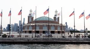Aon Grand Ballroom at Navy Pier with Chicago Skyline A postcard view of the Aon Grand Ballroom at Navy Pier from Lake Michigan, with the USS Chicago anchor, visitors along the seawall and nine flags flying against the Chicago skyline. Seven American flags join the Chicago and Illinois flags beneath a pale evening sky in Chicago, Illinois – © 2026 David Oppenheimer – Performance Impressions photography archives https://performanceimpressions.com Aon Grand Ballroom, 600 East Grand Avenue, Navy Pier, USS Chicago anchor, Chicago Warship Anchor, Chicago skyline, Chicago cityscape, Chicago postcard, Navy Pier postcard, Visit Chicago, Grand Ballroom, Navy Pier Auditorium, ballroom exterior, building exterior, facade, skyline, city skyline, cityscape, skyline view, Chicago skyline view, waterfront skyline, lakefront skyline, urban skyline, city view, lake view, postcard view, postcard image, postcard, Chicago waterfront, Chicago lakefront, Lake Michigan, flags, flag, American flag, American flags, U.S. flag, U.S. flags, USA flag, United States flag, Stars and Stripes, Chicago flag, Chicago city flag, city flag, red stars, Illinois flag, Illinois state flag, state flag, Illinois state seal, Illinois seal, flagpoles, flags flying, flags in wind, windblown flags, nine flags, seven American flags, waterfront promenade, seawall, visitors, tourists, people, evening, pale sky, Chicago tourism, Chicago travel, Chicago vacation, Chicago destination, Chicago attractions, Chicago landmarks, things to do in Chicago, tourist attraction, tourist destination, travel destination, sightseeing, tourism, travel, vacation, destination, iconic Chicago, Windy City, Illinois tourism, Midwest travel, Great Lakes tourism, Streeterville, Chicago, Illinois, Cook County, architecture, historic architecture, Chicago Landmark, Arts and Crafts architecture, twin towers, concert hall towers, tower lanterns, domed ballroom, Charles Sumner Frost, Frost and Granger, Edward C. Shankland, William Artingstall, Municipal Pier, Municipal Pier No. 2, Navy Pier Observation Deck, Offshore Rooftop, Offshore Rooftop and Bar, Bob Newhart Statue, Aon, Aon plc, Great Lakes, Midwest, USA, United States, 60611, travel photography, tourism photography, postcard photography, cityscape photography, destination imagery, landmark photography, Licensing, image licensing, commercial imagery, photography licensing, art, print, fine art, commercial photography, David Oppenheimer, horizontal, 1-15213827141