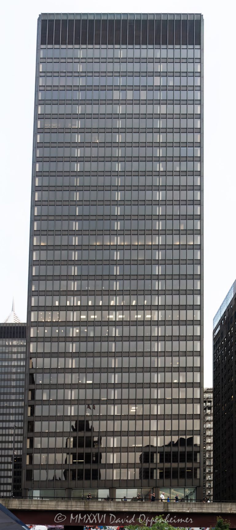 150 North One Illinois Center at 111 East Wacker Drive in Chicago’s Loop shows the modernist office tower’s bronze-anodized aluminum exterior and tinted-glass curtain wall. Designed by Ludwig Mies van der Rohe for Metropolitan Structures and completed under Joseph Fujikawa of The Office of Mies van der Rohe, the building is also known as 111 East Wacker and was the first tower constructed in the Illinois Center complex – © 2026 David Oppenheimer – Performance Impressions photography archives https://performanceimpressions.com One Illinois Center, One Illinois Center Chicago, One Illinois Center building, 1 Illinois Center, 111 East Wacker, 111 East Wacker Drive, 111 E Wacker Drive, 111 E Wacker Dr, 111 E Wacker, 111 East Wacker Building, Illinois Center, Illinois Center Chicago, Illinois Center complex, Illinois Center office tower, East Wacker Drive, Wacker Drive, Chicago Loop, Loop Chicago, East Loop, downtown Chicago, Chicago Illinois, Chicago IL, 60601, facade, building exterior, exterior, modernist facade, bronze facade, bronze aluminum, anodized aluminum, tinted glass, tinted windows, glass facade, glass curtain wall, curtain wall, steel and glass, exposed columns, office tower, office building, commercial building, commercial office, Class A office, skyscraper, high rise, tower, building, office, commercial, real estate, Chicago real estate, commercial real estate, office real estate, downtown real estate, architecture, architectural photography, Chicago architecture, modern architecture, modernist architecture, Modernism, International Style, Miesian architecture, midcentury modern, commercial architecture, office architecture, Ludwig Mies van der Rohe, Mies van der Rohe, Mies, Mies building, Mies Chicago, Joseph Fujikawa, The Office of Mies van der Rohe, Metropolitan Structures, Chicago Architecture Center, CAC Chicago, Illinois architecture, United States, licensing, image licensing, commercial imagery, photography licensing, art, print, fine art, commercial photography, David Oppenheimer, vertical, 1-15213827141