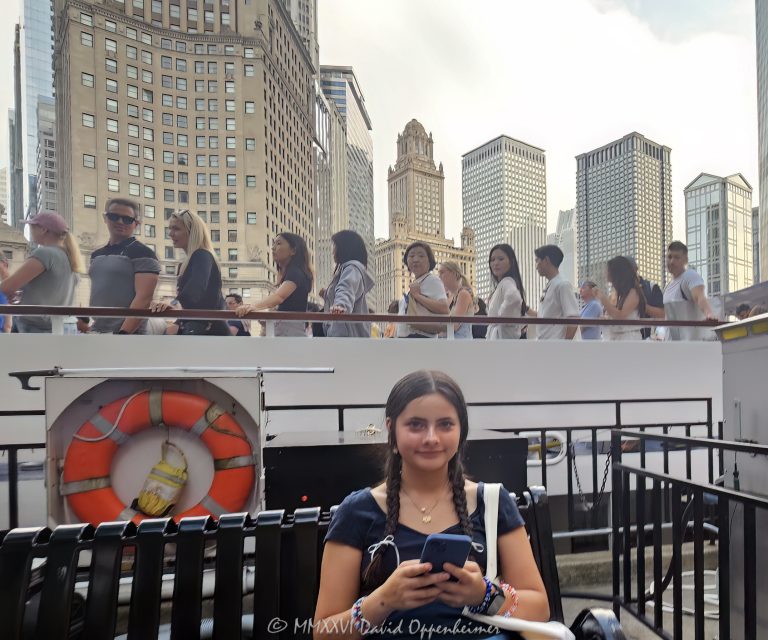 Chicago architecture cruise on the Chicago River in downtown Chicago, Illinois, with a young visitor seated in the foreground and tourists aboard a riverboat against the Wacker Drive skyline. LondonHouse Chicago, The Royal Sonesta Chicago Downtown, the Jewelers Building, One East Wacker, the Leo Burnett Building and 77 West Wacker rise behind the boat, creating a quintessential Chicago tourism and riverfront architecture scene – © 2026 David Oppenheimer – Performance Impressions photography archives https://performanceimpressions.com Chicago architecture cruise, architecture cruise, Chicago river cruise, Chicago River, Chicago architecture, Chicago architecture tour, architecture tour, Chicago architecture boat tour, architecture boat tour, Chicago River boat tour, Chicago River architecture cruise, Chicago boat tour, boat tour, river cruise, river tour, riverboat, tour boat, passenger boat, boat, cruise, sightseeing cruise, sightseeing boat, sightseeing, Chicago sightseeing, Chicago tours, Chicago tour, Visit Chicago, visit Chicago, Chicago tourism, Chicago tourist, Chicago tourists, tourist, tourists, tourism, Chicago visitor, Chicago visitors, visitor, Chicago travel, Chicago trip, Chicago vacation, Chicago vacations, Chicago attractions, Chicago attraction, things to do Chicago, Chicago destination, downtown Chicago, Chicago Loop, Loop, Chicago, Illinois, Chicago River tourism, river tourism, riverfront, Chicago riverfront, waterfront, river view, architecture, buildings, Chicago buildings, skyscrapers, Chicago skyscrapers, skyscraper, towers, tower, high-rise, skyline, Chicago skyline, downtown skyline, cityscape, urban architecture, river architecture, riverfront architecture, Wacker Drive, Wacker architecture, girl, teenager, teen, young visitor, smartphone, cell phone, bench, family travel, travel, vacation, summer tourism, LondonHouse Chicago, LondonHouse, London House, LondonHouse hotel, LondonHouse Chicago Curio Collection by Hilton, Curio Collection, Hilton, Hilton hotel, Chicago hotel, riverfront hotel, HLT, NYSE HLT, London Guarantee Building, London Guarantee, 85 East Wacker, 85 E Wacker, Beaux Arts, Beaux Arts architecture, Alfred Alschuler, Goettsch Partners, The Royal Sonesta Chicago Downtown, Royal Sonesta, Sonesta Chicago, Sonesta, Sonesta hotel, 71 East Wacker, 71 E Wacker, downtown hotel, Jewelers Building, Jewelers Building Chicago, Jewelers, 35 East Wacker, 35 E Wacker, Pure Oil Building, North American Life Building, Chicago Landmark, Giaver & Dinkelberg, Giaver Dinkelberg, Joachim Giaver, Frederick Dinkelberg, terra cotta, historic architecture, historic building, One East Wacker, 1 East Wacker, One E Wacker, Kemper Building, Kemper, Shaw Metz Associates, Shaw Metz, office tower, marble facade, Leo Burnett Building, Leo Burnett, 35 West Wacker, 35 W Wacker, Roche Dinkeloo, Kevin Roche, John Dinkeloo, postmodern, postmodern architecture, 77 West Wacker, 77 W Wacker, RR Donnelley Building, R.R. Donnelley Building, RR Donnelley, United Building, Ricardo Bofill, Bofill, office building, commercial architecture, Chicago hotels, United States, USA, Chicago photography, architecture photography, river photography, travel photography, tourism photography, street photography, lifestyle photography, editorial photography, cityscape photography, architectural photography, fine art photography, Chicago art, architecture art, Chicago print, river art, photographic print, fine art print, archival print, gallery print, collector print, wall art, licensing, image licensing, commercial imagery, photography licensing, art, print, fine art, commercial photography, David Oppenheimer, Performance Impressions, Performance Impressions photography archives, horizontal, 1-15213827141