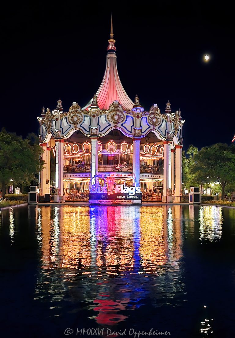 Columbia Carousel at Six Flags Great America near Chicago in Gurnee, Illinois, illuminated at night and mirrored across the Carousel Plaza reflecting pool. The entire double-decker carousel and glowing Six Flags Great America sign are reflected in the water, where colorful lights stretch into vertical columns of red, yellow, blue and other colors, creating a symmetrical fine-art view of the landmark amusement park attraction – © 2026 David Oppenheimer – Performance Impressions photography archives https://performanceimpressions.com Columbia Carousel, Columbia Carousel reflection, Six Flags Great America, Six Flags Great America reflection, Six Flags Great America Chicago, Great America Chicago, Six Flags Chicago, Six Flags Illinois, Great America Illinois, Six Flags, Great America, Six Flags sign, Six Flags Great America sign, Great America sign, illuminated sign, park sign, branding, Six Flags branding, Columbia Carousel Chicago, Chicago carousel, Columbia, carousel, carousel reflection, carousel lights, illuminated carousel, carousel night, carousel ride, double-decker carousel, double deck carousel, two-level carousel, merry-go-round, merry go round, classic carousel, carousel attraction, amusement ride, family ride, Carousel Plaza, Six Flags Carousel Plaza, reflecting pool, reflection pool, reflecting pond, mirror reflection, mirrored reflection, water reflection, carousel reflection, reflections, reflection, reflected lights, light reflection, colorful reflection, colorful reflections, symmetrical reflection, symmetry, mirror image, mirrored, water, illuminated, illumination, lights, colored lights, colorful lights, vertical reflections, light columns, colored columns, glowing lights, park lights, amusement park lights, carnival lights, night lights, nighttime, night, evening, after sunset, dusk, amusement park, theme park, amusement parks, theme parks, amusement, attraction, attractions, park attraction, amusement park attraction, theme park attraction, landmark attraction, Gurnee, Gurnee Illinois, Gurnee IL, Illinois, Lake County, Lake County Illinois, northern Illinois, Chicagoland, Chicago area, Chicago, Chicago Illinois, Chicago theme park, Chicago amusement park, Chicago attraction, Chicago attractions, Illinois attraction, Illinois attractions, Gurnee attraction, Midwest, Midwest attraction, Midwest theme park, Midwest amusement park, Chicago tourism, Chicago travel, Chicago trip, Chicago vacation, Visit Chicago, visit Chicago, Illinois tourism, Illinois travel, Visit Illinois, Gurnee tourism, tourist attraction, travel destination, destination, travel, tourism, sightseeing, summer, summer evening, summer night, Great America Parkway, 1 Great America Parkway, Grand Avenue, Route 132, Interstate 94, I-94, 60031, Chance, carousel manufacturer, Marriott’s Great America, Marriotts Great America, Marriott Great America, historic Great America, Six Flags Entertainment Corporation, Six Flags Entertainment, Six Flags company, NYSE FUN, FUN, Six Flags stock, United States, USA, abstract, abstract reflection, abstract lights, abstract photography, geometric, geometry, symmetry photography, reflection photography, night photography, low light photography, carousel photography, amusement park photography, theme park photography, architectural photography, travel photography, tourism photography, editorial photography, fine art photography, Six Flags photography, Great America photography, carousel art, reflection art, abstract art, amusement park art, theme park art, Six Flags art, Great America art, Chicago art, Illinois art, carousel print, reflection print, amusement park print, theme park print, Six Flags print, Great America print, photographic print, fine art print, archival print, gallery print, collector print, wall art, office art, licensing, image licensing, commercial imagery, photography licensing, art, print, fine art, commercial photography, David Oppenheimer, Performance Impressions, Performance Impressions photography archives, horizontal, 1-15213827141