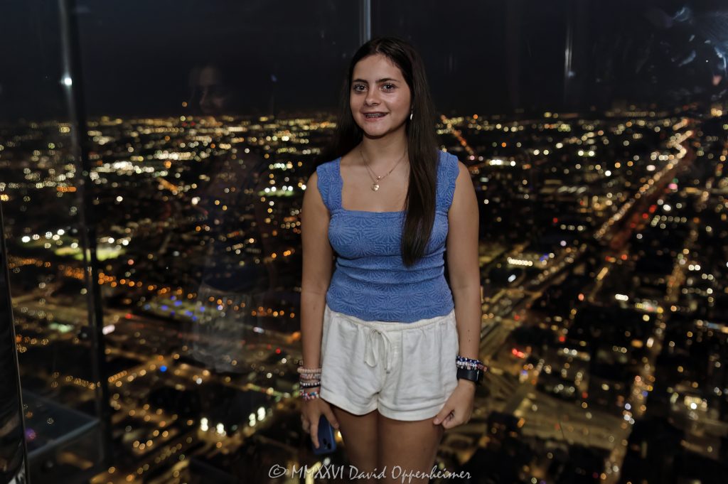 Skydeck Chicago’s Ledge at Willis Tower shows a person inside the glass observation box at night, with transparent floor panels, glass walls, and Chicago city lights beyond the 103rd-floor view. Located at 233 South Wacker Drive, the landmark skyscraper was formerly known as Sears Tower and remains one of Chicago’s best-known observation deck attractions – © 2026 David Oppenheimer – Performance Impressions photography archives https://performanceimpressions.com Skydeck Chicago, Skydeck Chicago Ledge, The Ledge, Willis Tower Skydeck, Willis Tower Ledge, Willis Tower, Sears Tower, former Sears Tower, Sears Tower Chicago, Willis Tower Chicago, 233 S Wacker Drive, 233 South Wacker Drive, 233 S Wacker Dr, South Wacker Drive, Wacker Drive, Chicago Loop, Loop Chicago, downtown Chicago, Chicago Illinois, Chicago IL, 60606, observation deck, observation, deck, glass observation deck, glass ledge, glass box, glass floor, glass walls, glass balcony, transparent floor, transparent walls, glass, floor, walls, night, nighttime, night photography, city lights, Chicago night, Chicago city lights, city view, skyline, skyline view, Chicago skyline, view, lookout, overlook, attraction, experience, vacation, tourism, travel, sightseeing, tourist, tourists, person, silhouette, standing, interior, tower, skyscraper, high rise, building, architecture, architectural photography, Chicago architecture, commercial architecture, modern architecture, Skidmore Owings Merrill, Skidmore Owings & Merrill, SOM, Bruce Graham, Fazlur Rahman Khan, Blackstone, EQ Office, real estate, Chicago real estate, landmark, Chicago landmark, United States, licensing, image licensing, commercial imagery, photography licensing, art, print, fine art, commercial photography, David Oppenheimer, horizontal, 1-15156784411