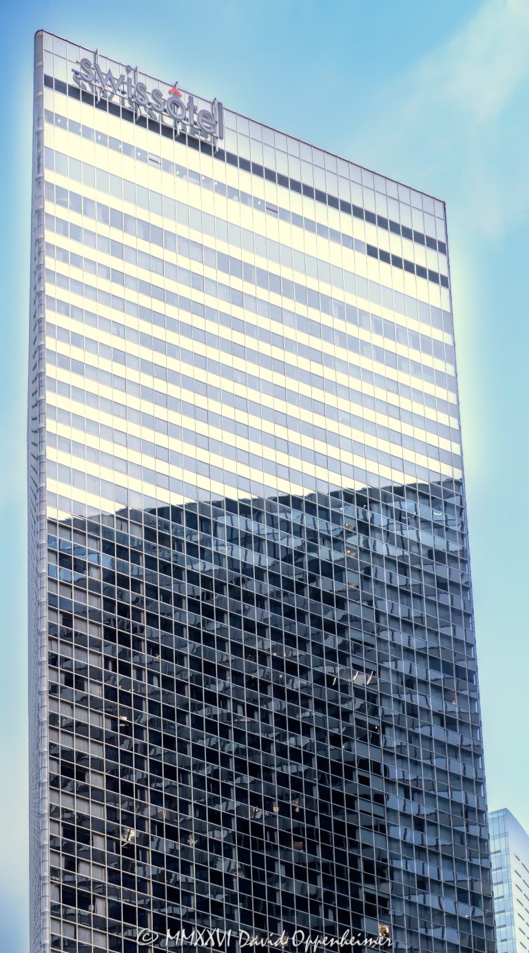 Swissôtel Chicago at 323 East Upper Wacker Drive is a luxury hotel in the Chicago Loop, occupying Harry Weese’s distinctive triangular all-glass tower overlooking the Chicago River and Lake Michigan. Its reflective facade and rooftop Swissôtel sign give the downtown high-rise a recognizable architectural identity near Millennium Park and the Magnificent Mile in Chicago, Illinois – © 2026 David Oppenheimer – Performance Impressions photography archives https://performanceimpressions.com Swissôtel Chicago, Swissotel Chicago, Swissôtel Chicago Hotel, Swissotel Chicago Hotel, Swissôtel, Swissotel, Swiss Hotel Chicago, 323 East Upper Wacker Drive, 323 E Upper Wacker Drive, 323 E Upper Wacker Dr, 323 East Wacker Drive, 323 E Wacker Drive, East Wacker Drive, Upper Wacker Drive, Wacker Drive, Chicago Loop, Loop Chicago, downtown Chicago, Lakeshore East, New Eastside, Chicago River, Chicago Riverwalk, Riverwalk, Lake Michigan, Chicago lakefront, Millennium Park, Magnificent Mile, Navy Pier, Chicago, Chicago Illinois, Chicago IL, Illinois, 60601, facade, building exterior, exterior, tower exterior, hotel exterior, upper tower, glass facade, glass tower, all-glass tower, glass hotel, glass curtain wall, curtain wall, reflective glass, mirrored glass, faceted facade, angular facade, triangular tower, triangular building, triangular form, geometric tower, rooftop sign, Swissôtel sign, hotel sign, building signage, luxury hotel, Chicago hotel, Chicago luxury hotel, downtown hotel, Chicago Loop hotel, downtown Chicago hotel, riverfront hotel, waterfront hotel, Lake Michigan hotel, Magnificent Mile hotel, Millennium Park hotel, business hotel, convention hotel, Four Diamond hotel, hotel tower, hotel, hospitality, luxury hospitality, Swiss hospitality, lodging, accommodation, business travel, travel, tourism, skyscraper, high rise, tower, building, commercial building, hospitality building, architecture, architectural photography, Chicago architecture, hotel architecture, hospitality architecture, commercial architecture, glass architecture, modern architecture, contemporary architecture, geometric architecture, high-rise architecture, Harry Weese, Harry Weese Associates, Swissôtel Hotels & Resorts, Accor, Accor Group, Accor SA, ALL Accor, ALL Accor Live Limitless, Accor stock, Euronext Paris AC, AC stock, ACCYY, ACCYY stock, Host Hotels & Resorts, Host Hotels, Host Hotels stock, NASDAQ HST, HST stock, HST, The Palm Chicago, Amuse Chicago, hotel ownership, hotel real estate, Chicago real estate, hospitality real estate, commercial real estate, riverfront real estate, pale blue sky, summer clouds, low clouds, misty clouds, atmospheric sky, Illinois architecture, United States, licensing, image licensing, commercial imagery, photography licensing, art, print, fine art, commercial photography, David Oppenheimer, vertical, 1-15213827141