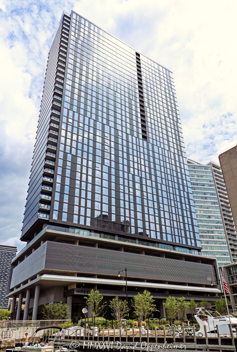 The Reed at Southbank at 234 West Polk Street rises in Chicago’s South Loop, with its industrial-modern residential tower facade overlooking Polk Street Pier and River City Marina. Developed and constructed by Lendlease with architecture by Perkins&Will, the riverfront high-rise includes both apartments and condominiums within the larger Southbank neighborhood development – © 2026 David Oppenheimer – Performance Impressions photography archives https://performanceimpressions.com The Reed, The Reed Chicago, The Reed at Southbank, The Reed Apartments, The Reed Condos, Reed Apartments, Reed Condos, 234 W Polk Street, 234 West Polk Street, 234 W Polk St, Southbank Chicago, Southbank, South Loop, South Loop Chicago, downtown Chicago, Chicago Illinois, Chicago IL, 60607, Polk Street, West Polk Street, Chicago River, river, riverfront, waterfront, Chicago riverfront, Chicago waterfront, Polk Street Pier, River City Marina, F Dock, marina, dock, pier, boat slips, boats, water, waterway, facade, building exterior, exterior, residential facade, glass facade, industrial modern, tower, residential tower, apartment tower, condo tower, high rise, skyscraper, residential building, apartment building, condominium building, apartments, condos, condominiums, rental apartments, luxury apartments, luxury condos, real estate, Chicago real estate, South Loop real estate, residential real estate, riverfront real estate, waterfront real estate, housing, residential housing, architecture, architectural photography, Chicago architecture, riverfront architecture, residential architecture, contemporary architecture, Perkins&Will, Perkins and Will, Lendlease, Southbank development, Riverline, CMK Companies, urban waterfront, urban living, city living, Illinois architecture, United States, licensing, image licensing, commercial imagery, photography licensing, art, print, fine art, commercial photography, David Oppenheimer, vertical, 1-15156784411