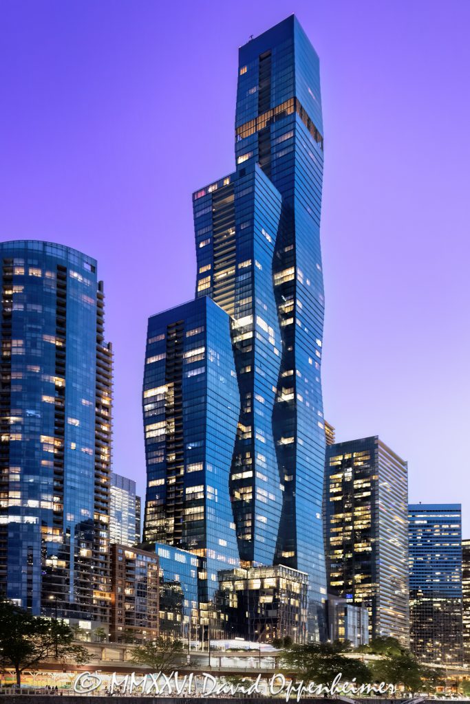 The St. Regis Chicago at 401 East Upper Wacker Drive rises above Lakeshore East at twilight, its illuminated windows articulating three interconnected volumes of blue-green glass against a purple post-sunset sky. Viewed from the Chicago River, the 101-story luxury hotel and condominium tower designed by Jeanne Gang of Studio Gang forms a sculptural landmark near Lake Michigan in Chicago, Illinois – © 2026 David Oppenheimer – Performance Impressions photography archives https://performanceimpressions.com The St. Regis Chicago, St. Regis Chicago, The St. Regis Chicago Hotel, St. Regis Hotel Chicago, The Residences at The St. Regis Chicago, St. Regis Chicago Residences, St. Regis Hotels & Resorts, 401 East Upper Wacker Drive, 401 E Upper Wacker Drive, 401 E Upper Wacker Dr, 401 East Wacker Drive, 401 E Wacker Drive, 363 East Wacker Drive, 363 E Wacker Drive, Vista Tower, Vista Tower Chicago, Wanda Vista Tower, Lakeshore East, Lakeshore East Chicago, New Eastside, Chicago Loop, Loop Chicago, downtown Chicago, East Wacker Drive, Upper Wacker Drive, Wacker Drive, Chicago River, Chicago Riverwalk, Riverwalk, riverfront, Lake Michigan, Chicago lakefront, DuSable Harbor, Navy Pier, Millennium Park, Chicago, Chicago Illinois, Chicago IL, Illinois, 60601, facade, building exterior, exterior, tower exterior, upper tower, glass facade, glass tower, glass towers, glass skyscraper, glass curtain wall, curtain wall, blue-green glass, gradient glass, aqua glass, reflective glass, high-performance glass, faceted facade, sculptural facade, geometric facade, three-volume tower, interconnected volumes, three towers, stacked frustums, frustum geometry, truncated pyramids, stepped edges, tapered tower, illuminated facade, illuminated windows, building lights, window lights, facade lighting, city lights, reflections, twilight, Chicago twilight, purple twilight, purple sky, post-sunset sky, dusk, after sunset, evening, skyline lights, luxury hotel, five-star hotel, Chicago hotel, Chicago luxury hotel, downtown hotel, riverfront hotel, Lake Michigan hotel, Marriott hotel, hotel tower, hotel, hospitality, luxury hospitality, St. Regis Butler Service, Marriott International, Marriott Bonvoy, Marriott stock, NASDAQ MAR, MAR stock, mixed-use tower, mixed-use building, condominium tower, residential tower, condominiums, luxury condos, luxury residences, Chicago condos, Lakeshore East condos, skyscraper, supertall, high rise, tower, building, 101-story tower, Chicago skyline, Chicago cityscape, skyline, cityscape, urban, city views, river views, lake views, real estate, Chicago real estate, Lakeshore East real estate, hotel real estate, hospitality real estate, condominium real estate, residential real estate, luxury real estate, riverfront real estate, commercial real estate, contemporary architecture, modern architecture, sculptural architecture, geometric architecture, high-rise architecture, riverfront architecture, Chicago architecture, architectural photography, architecture, engineering, structural engineering, wind engineering, reinforced concrete, blow-through floor, tuned liquid dampers, Studio Gang, Jeanne Gang, bKL Architecture, bKL Architects, Gensler, HBA, Magnusson Klemencic Associates, MKA, McHugh Construction, Power Construction, OLIN, Magellan Development Group, Gencom, GD Holdings, Gencom GD Holdings, hotel ownership, hotel investment, boat view, river view, Chicago River cruise, architecture cruise, urban photography, twilight photography, hotel photography, United States, licensing, image licensing, commercial imagery, photography licensing, art, print, fine art, commercial photography, David Oppenheimer, vertical, 1-15213827141