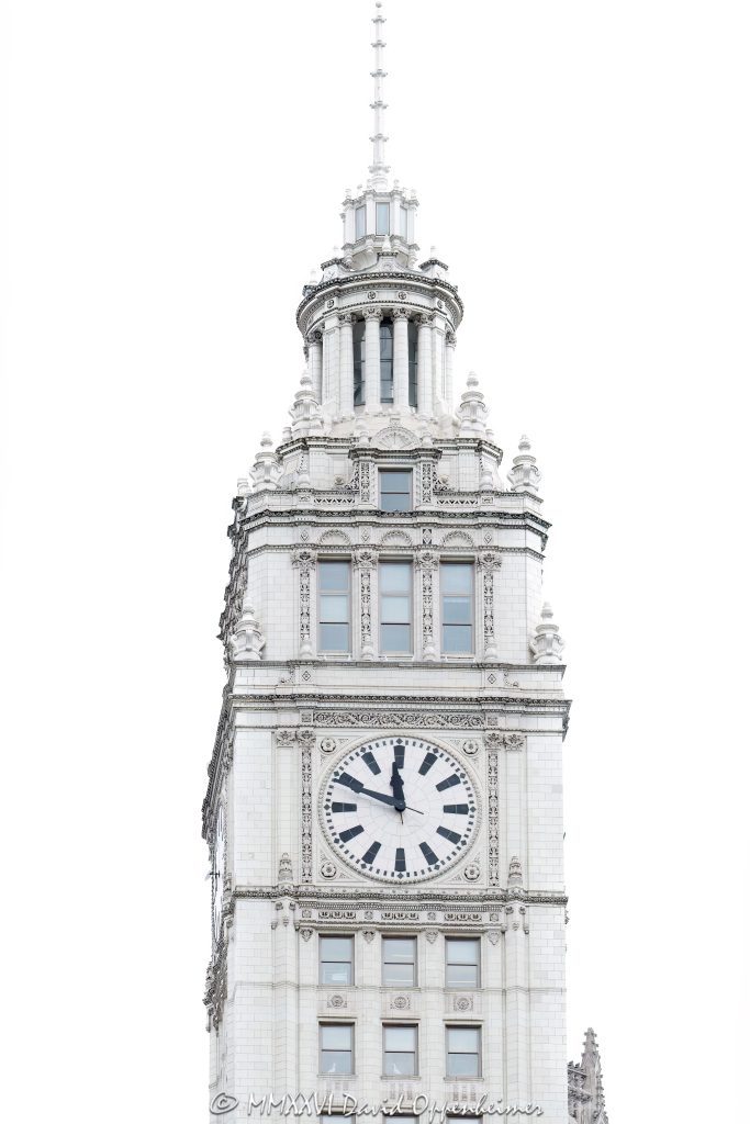 Wrigley Building clock tower rises above North Michigan Avenue along the Chicago River, featuring its white glazed terra cotta facade and prominent four-faced clock, a defining element of this historic Chicago landmark designed by Graham, Anderson, Probst & White for William Wrigley Jr. – © 2026 David Oppenheimer – Performance Impressions photography archives https://performanceimpressions.com Wrigley Building, Wrigley Building Chicago, Wrigley Building clock tower, 400 North Michigan Avenue, 410 North Michigan Avenue, 400-410 North Michigan Avenue, North Michigan Avenue, Michigan Avenue, Chicago River, riverfront, downtown Chicago, Chicago, Chicago Illinois, Chicago IL, Illinois, 60611, clock tower, clock, clock face, tower detail, facade, building exterior, exterior, white terra cotta, glazed terra cotta, terra cotta facade, white facade, ornate facade, historic facade, landmark building, Chicago Landmark, historic building, tower, north tower, south tower, skyscraper, high rise, office building, commercial building, Wrigley Company, Wm Wrigley Jr Company, William Wrigley Jr, architecture, architectural photography, Chicago architecture, historic architecture, riverfront architecture, commercial architecture, Spanish Colonial Revival, French Renaissance Revival, Graham Anderson Probst & White, Graham Anderson Probst White, Alfred P Shaw, Chicago history, Illinois architecture, United States, licensing, image licensing, commercial imagery, photography licensing, art, print, fine art, commercial photography, David Oppenheimer, 1-15213827141