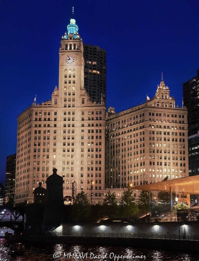 The Wrigley Building at 400–410 North Michigan Avenue glows above the Chicago River at night, its white glazed terra cotta facade, clock tower, and illuminated riverfront profile reflected in the water near DuSable Bridge. Designed by Graham, Anderson, Probst & White for William Wrigley Jr., the former Wrigley Company headquarters remains one of Chicago, Illinois’s defining landmarks on the Magnificent Mile – © 2026 David Oppenheimer – Performance Impressions photography archives https://performanceimpressions.com