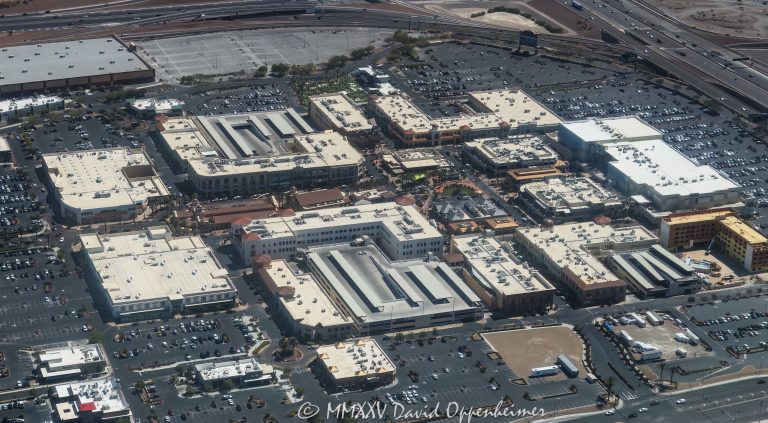 Town Square Las Vegas outdoor shopping center at 6605 Las Vegas Blvd South in Las Vegas, Nevada aerial view – © 2025 David Oppenheimer – Performance Impressions aerial photography archives – https://performanceimpressions.com Town Square, Town Square Las Vegas, Town Square Las Vegas aerial, Town Square Park, 6605 Las Vegas Blvd S, Las Vegas, 89119, Clark County, Nevada, United States, outdoor shopping center, retail dining entertainment, public park, central lawn, green space, water features, fountains, park, shopping, retail, outdoor, open-air, Whole Foods, Old Navy, H&M, TJ Max, Element Hotel, Saks Off 5th, splash pad, children’s park, playground, shade structures, palm trees, pedestrian streets, AMC Town Square 18, plazas, event space, lawn events, family friendly, restaurants, bars, movie theater, parking lots, ring roads, Las Vegas Boulevard, I-15, 215 Beltway, south Strip, urban park, landscape design, mixed-use, architecture, aerial, aerial view, horizontal, color, daytime, sunny, desert setting, Southwest, tourism, destination, travel, cityscape, metropolitan, commercial district, shopping precinct, entertainment district, pedestrian friendly, walkways, streetscape, The Guest House Las Vegas, open space, xeriscape, maintenance, management office, concierge, Town Square events, 702-269-5001, USA. horizontal, color, 1-14993092111